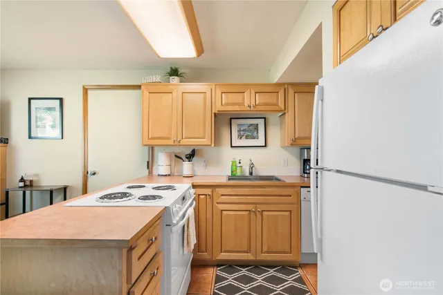 a kitchen with a sink a stove a refrigerator a washer dryer and white cabinets