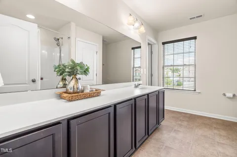a bathroom with a granite countertop sink a large mirror a and a window