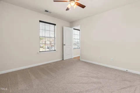 an empty room with chandelier fan and windows