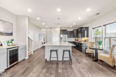 a kitchen with stainless steel appliances a dining table chairs stove refrigerator and cabinets