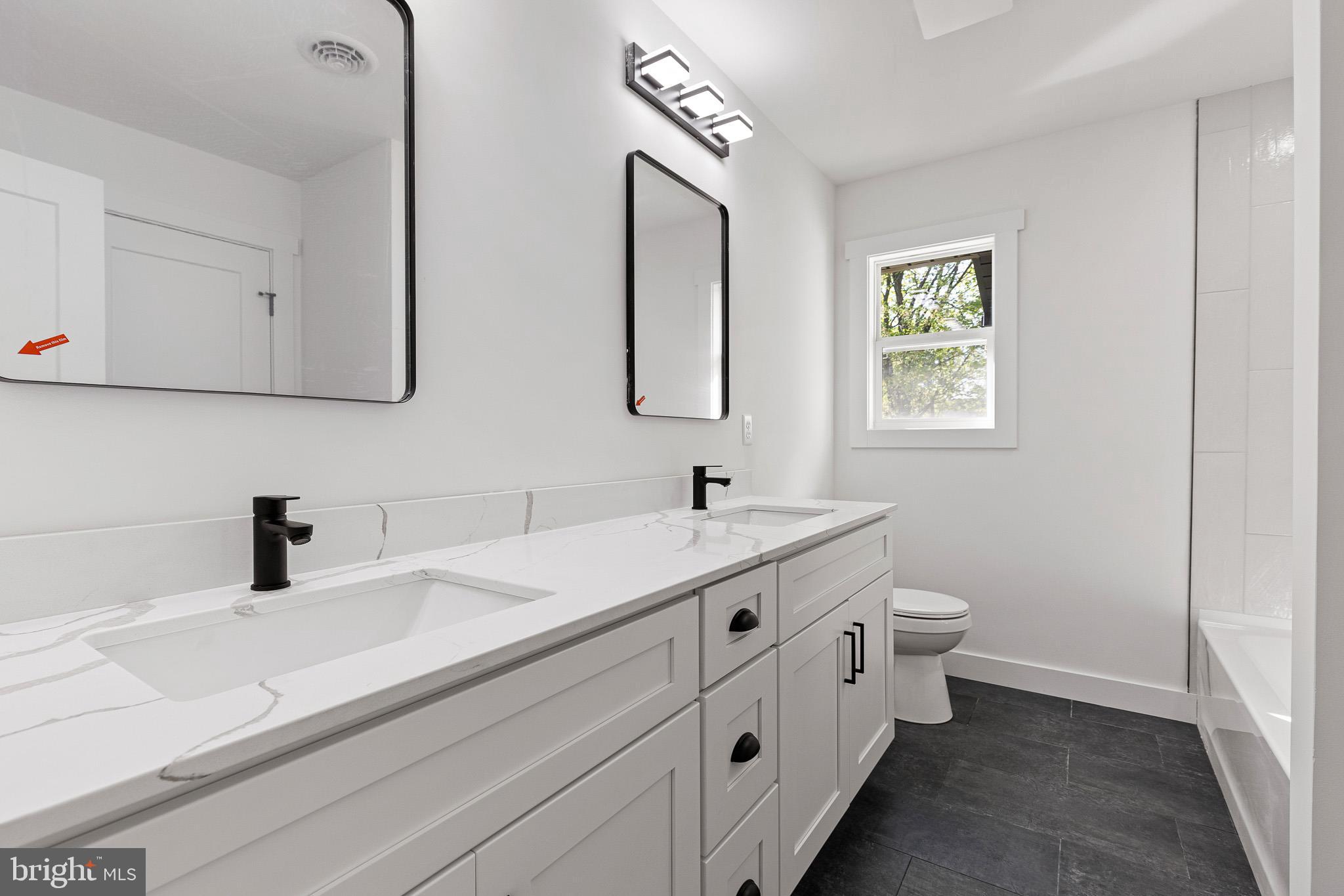 3 Queens Way Newark, DE 19713 - Photo 16 of 20 a bathroom with a double vanity sink a toilet and a window