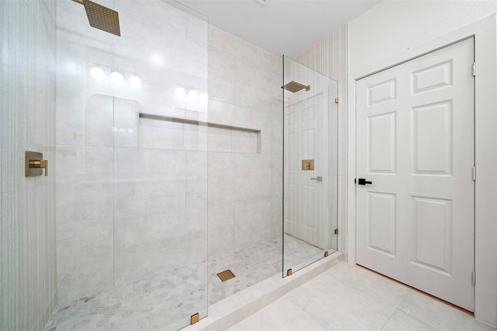 2104 Old McGarrah Road McKinney, TX 75072 - Photo 14 of 35 Glass-enclosed shower featuring a built-in niche, gold-finish fixtures, and a pebble tile shower floor