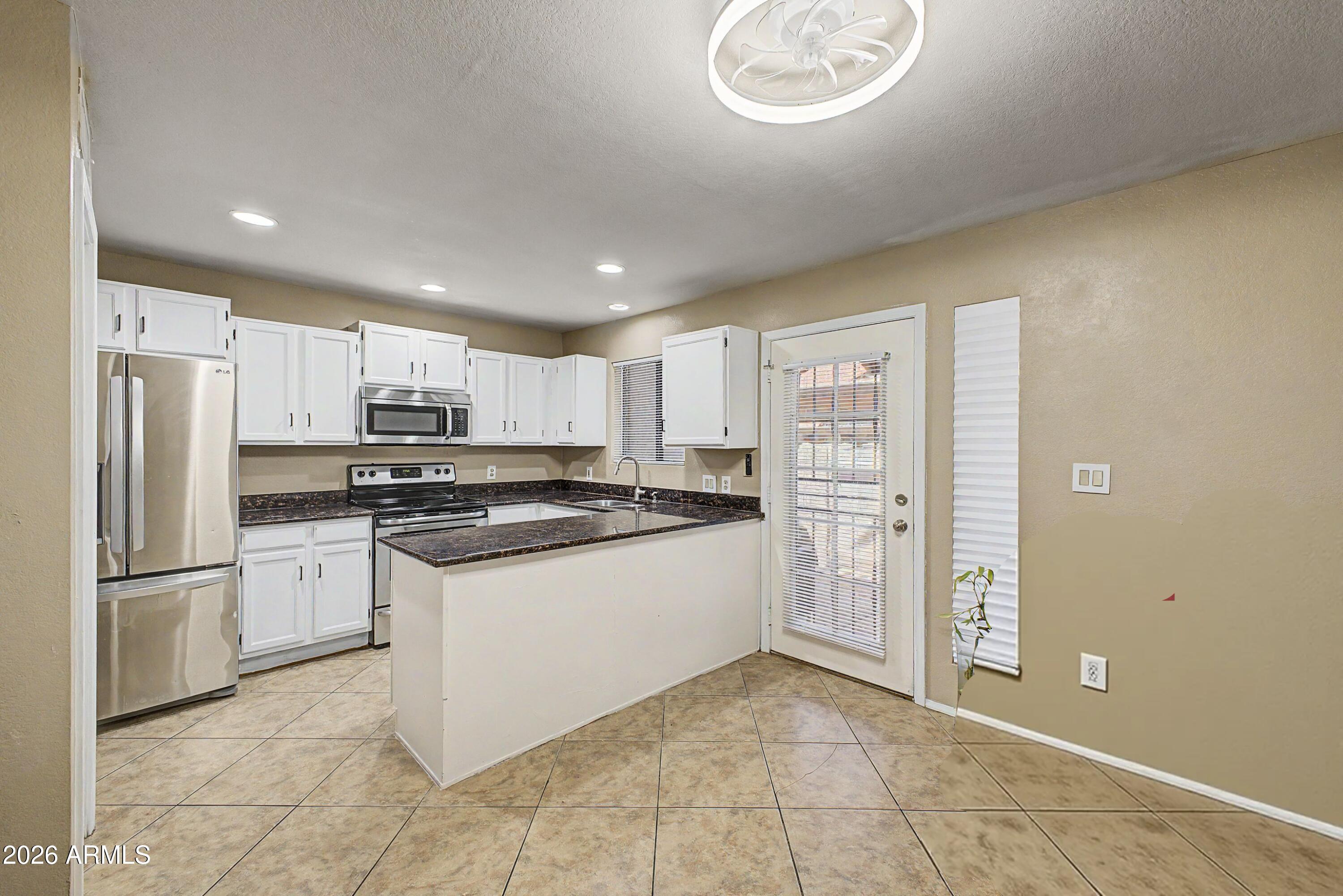 6262 East Brown Road, Unit 29 Mesa, AZ 85205 - Photo 15 of 59 a kitchen with stainless steel appliances granite countertop a refrigerator and a stove top oven
