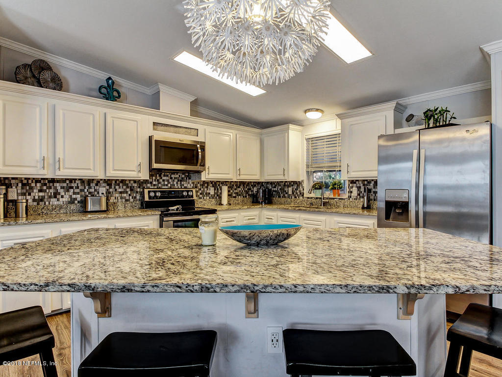 2244 Marlee Road South St. Johns, FL 32259 - Photo 5 of 38 a kitchen with kitchen island granite countertop a table chairs microwave and refrigerator