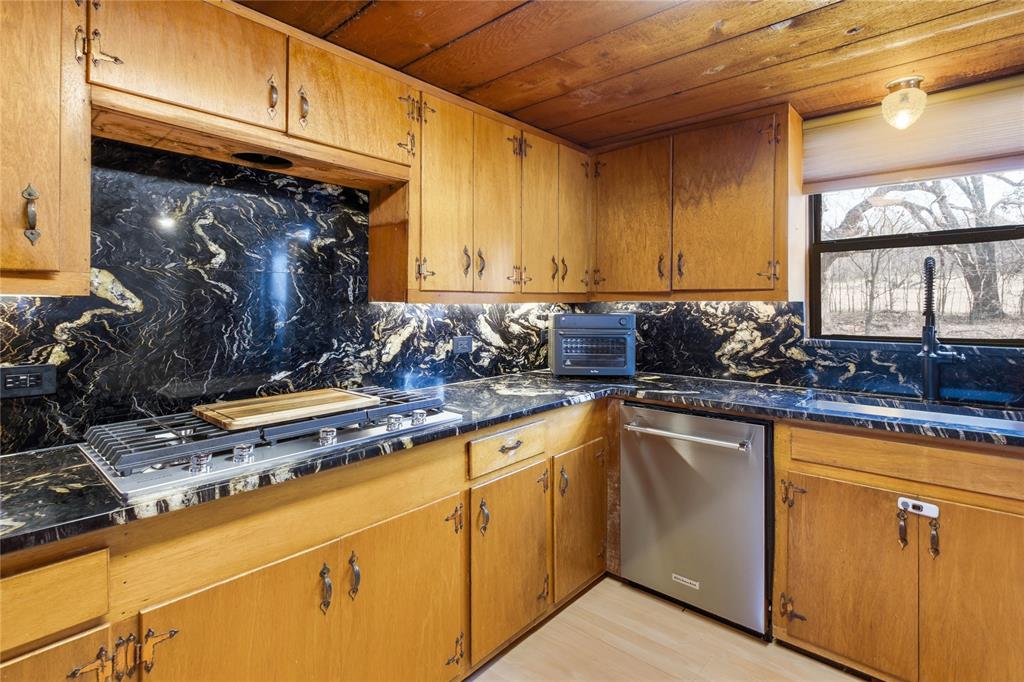 9213 Wilson Road Pilot Point, TX 76258 - Photo 13 of 38 9213 Wilson Road, Pilot Point, TX 76258 - kitchen - Kitchen with stainless steel appliances, wood finish cabinets, wood ceiling, dark stone counters, and light wood-type flooring