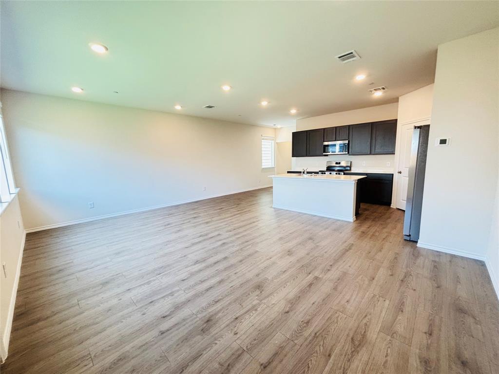 120 Redwood Road Princeton, TX 75407 - Photo 2 of 24 Open-concept living space featuring wood-finish flooring, recessed lighting, and a white kitchen island