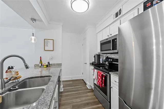 a kitchen with stainless steel appliances kitchen island granite countertop a sink and a refrigerator