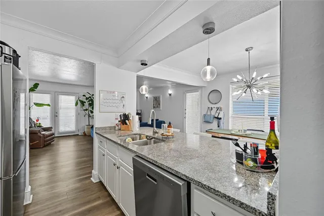 a open kitchen with stainless steel appliances granite countertop a sink dishwasher a stove and a dining table with wooden floor