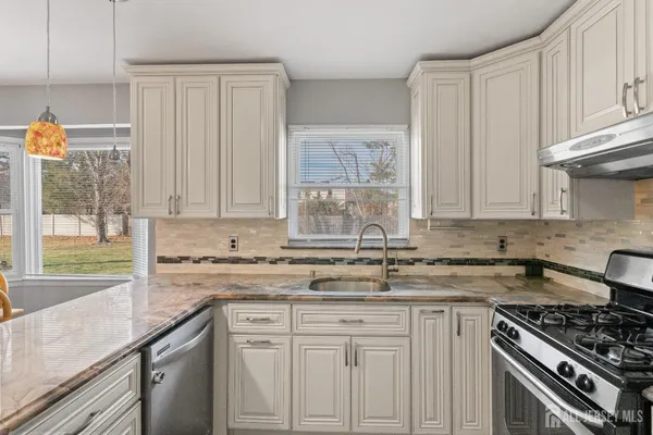 a kitchen with granite countertop a sink a stove and cabinets