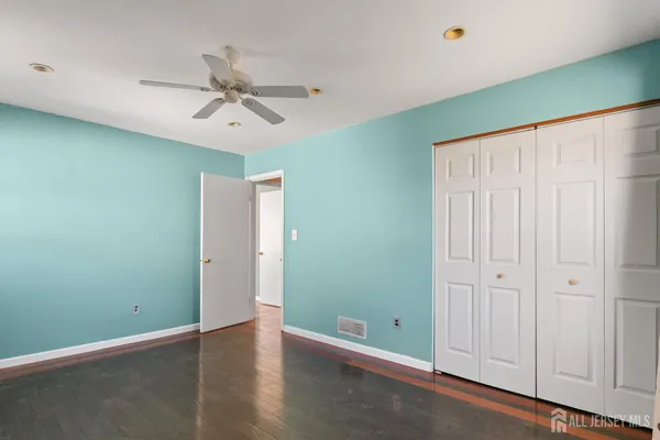 an empty room with closet and a ceiling fan
