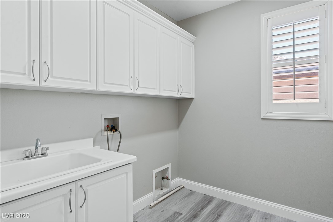 312 Pocono Ranch Avenue North Las Vegas, NV 89031 - Photo 29 of 34 Laundry area with a sink, light wood-style floors, baseboards, hookup for a washing machine, and cabinet space