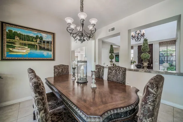 a dining room with wooden floor a chandelier a wooden table and chairs