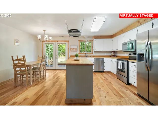 a kitchen with stainless steel appliances granite countertop a stove top oven a sink a dining table and chairs