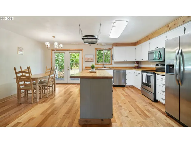 a kitchen with stainless steel appliances granite countertop a stove top oven a sink a dining table and chairs