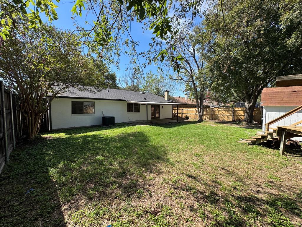 6645 Starnes Road Watauga, TX 76148 - Photo 13 of 18 Expansive backyard featuring a manicured lawn, established trees, and a wooden privacy fence