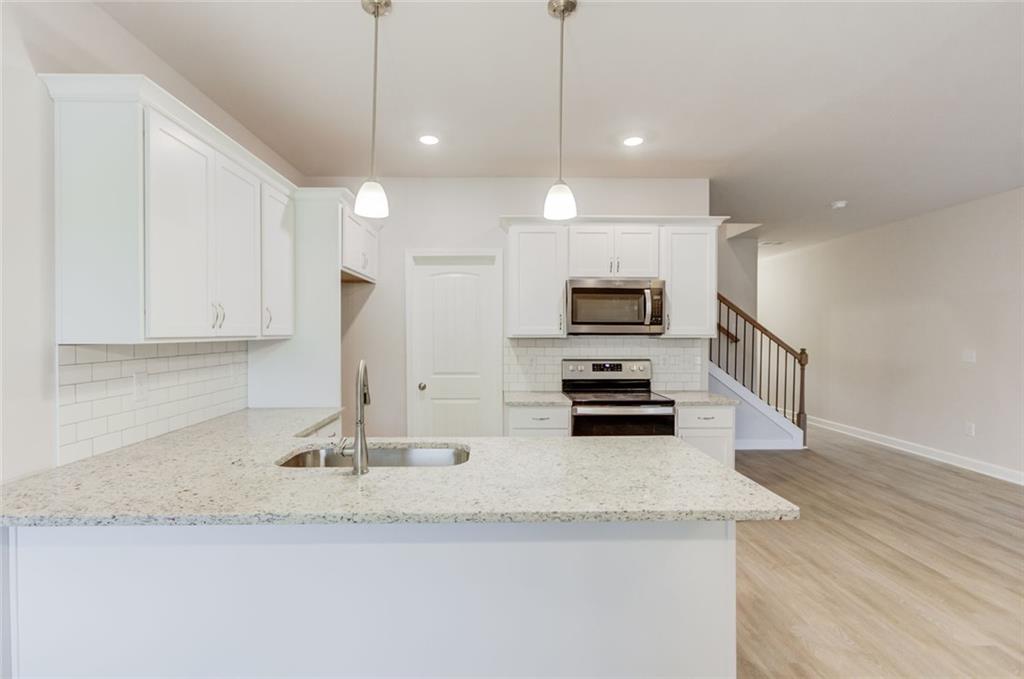 6354 Pine Ridge Point Lula, GA 30554 - Photo 11 of 33 a kitchen with stainless steel appliances granite countertop a sink a stove and a granite counter top