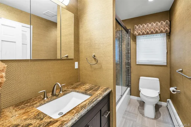 a bathroom with a granite countertop sink mirror vanity and toilet