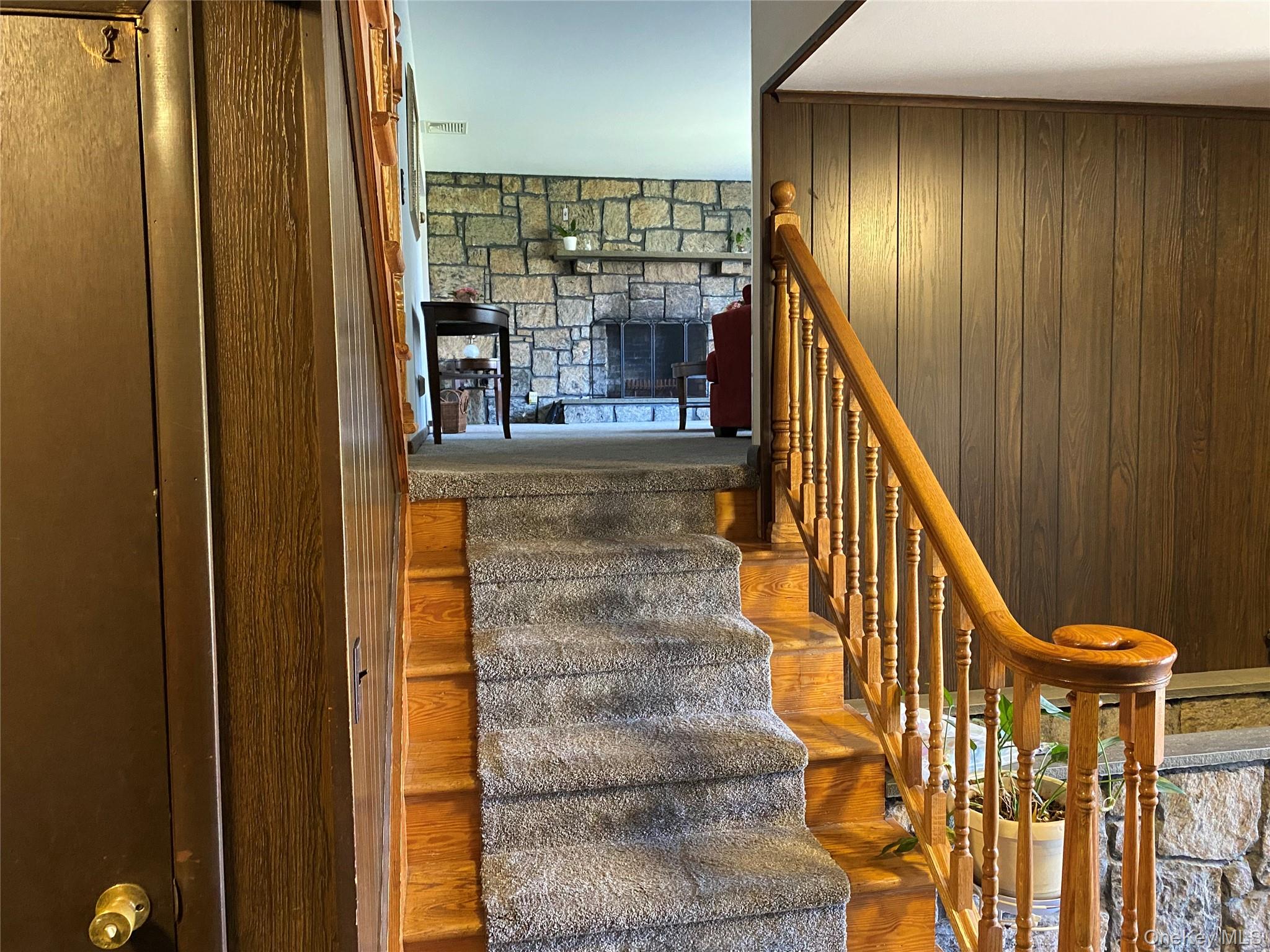 23 Colton Road Mahopac, NY 10541 - Photo 15 of 35 Staircase to Living Room from entry foyer featuring wood steps with carpeting, a wood banister, and wood paneling on the wall