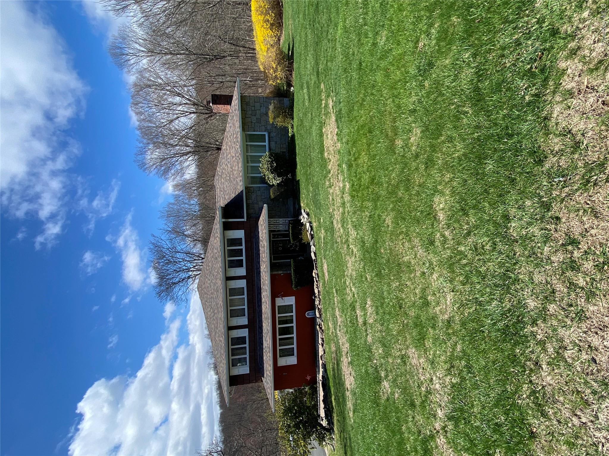 23 Colton Road Mahopac, NY 10541 - Photo 2 of 35 The property features an extensive lawn, a red siding facade, and a stone facade, complemented by a visible chimney