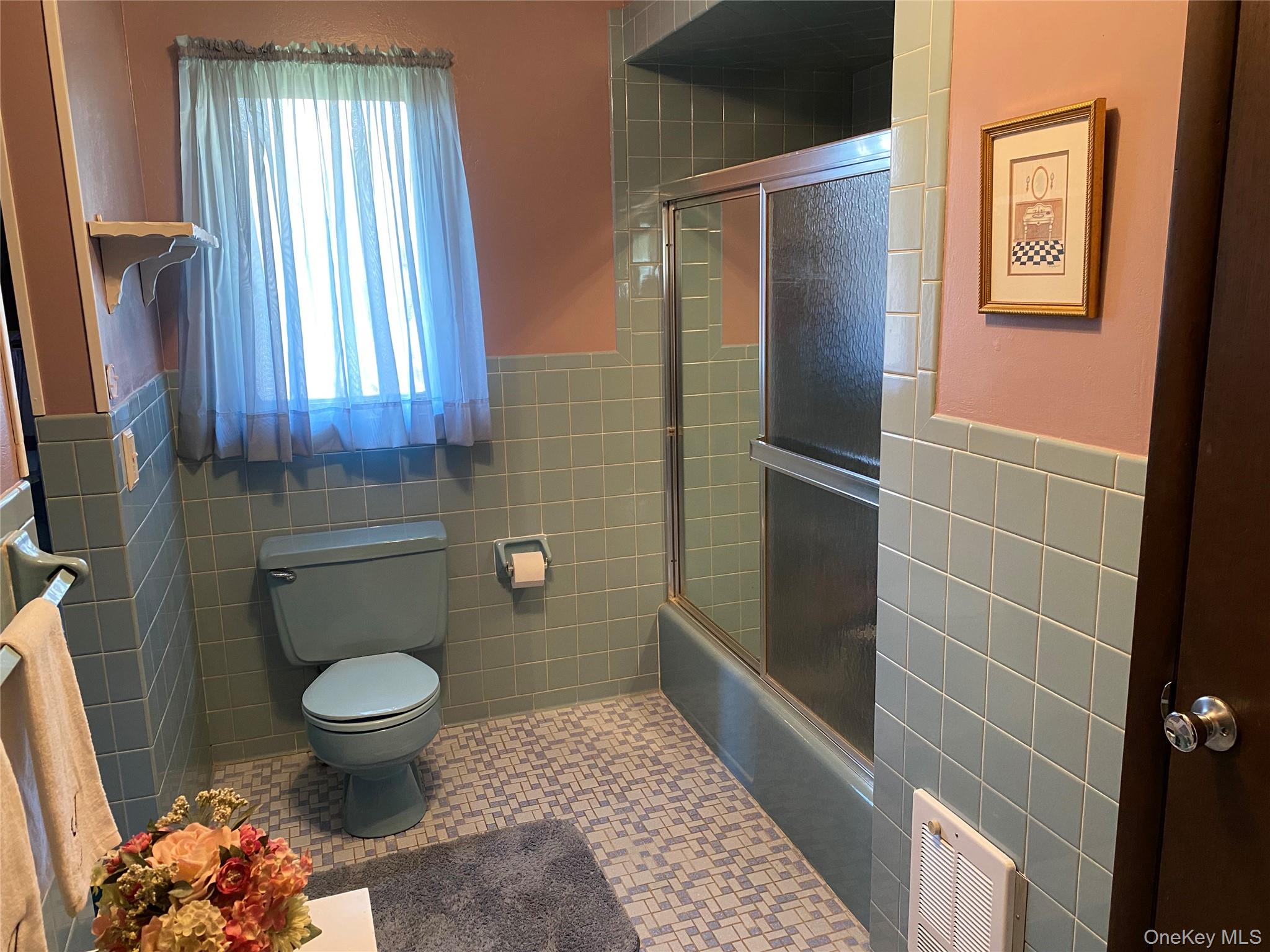23 Colton Road Mahopac, NY 10541 - Photo 29 of 35 The bathroom features light blue wall tiles, pink painted walls, a light blue toilet, and a shower with a sliding glass door