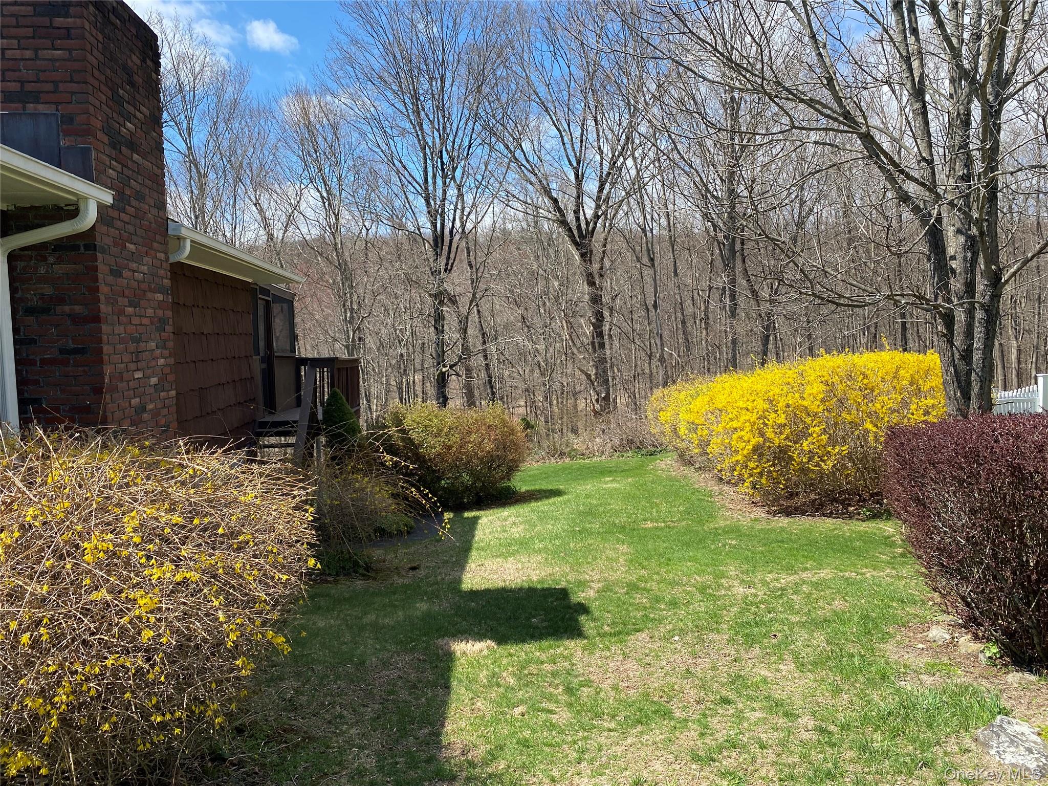23 Colton Road Mahopac, NY 10541 - Photo 6 of 35 The property features a brick chimney, a wood-sided exterior, and a wooden deck