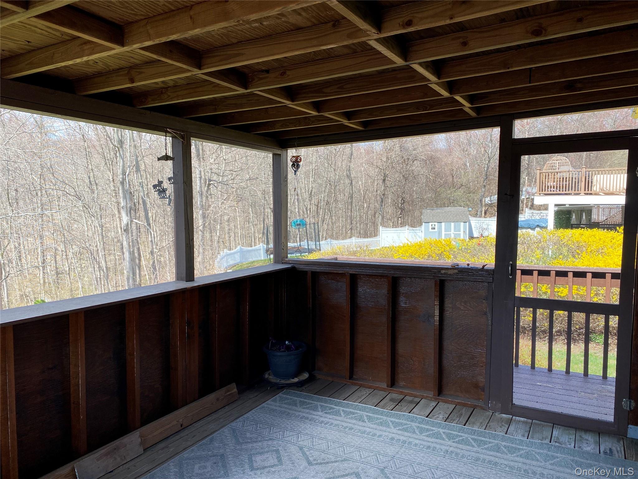 23 Colton Road Mahopac, NY 10541 - Photo 10 of 35 The screened porch features a wooden ceiling and offers views of mature trees and a vibrant yellow flowering bush