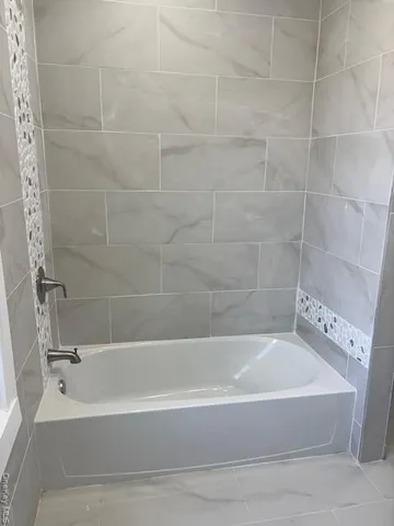 a white bath tub sitting next to a white sink and vanity