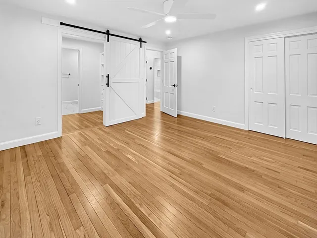 a view of an empty room with wooden floor and a bathroom