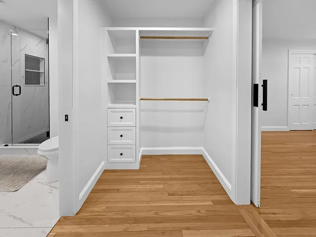 a view of a hallway with wooden floor and closet