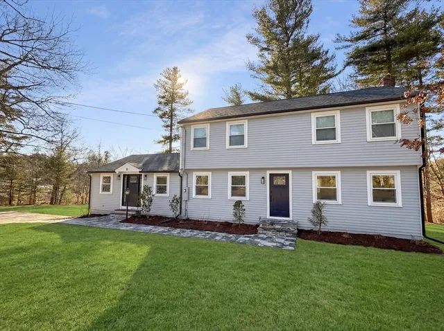 a front view of a house with a garden and trees