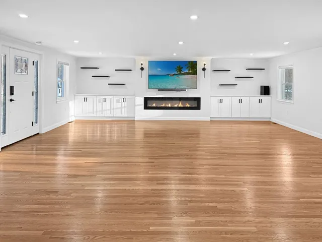 a view of kitchen and empty room with wooden floor