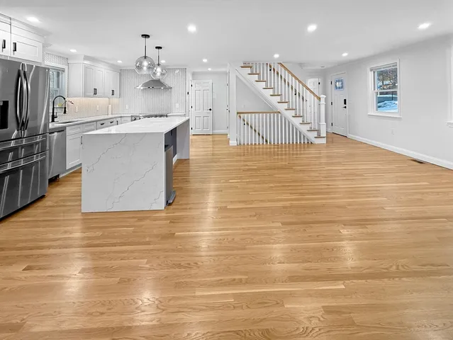 a large white kitchen with kitchen island a sink stainless steel appliances and cabinets