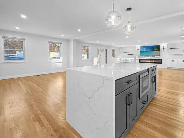 a large kitchen with stainless steel appliances a large counter top a sink and a living room view