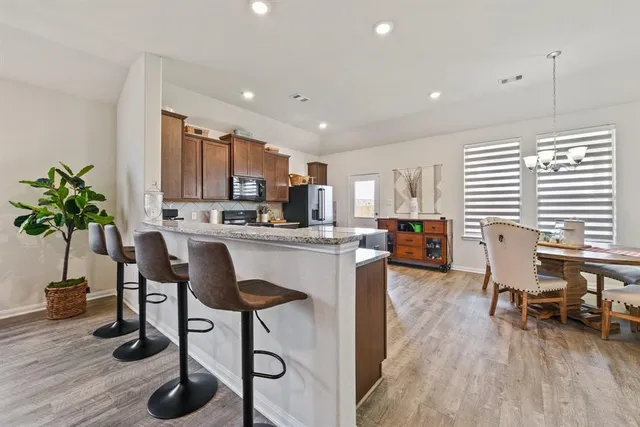 a living room with stainless steel appliances kitchen island granite countertop furniture a rug a potted plant and a wooden floor