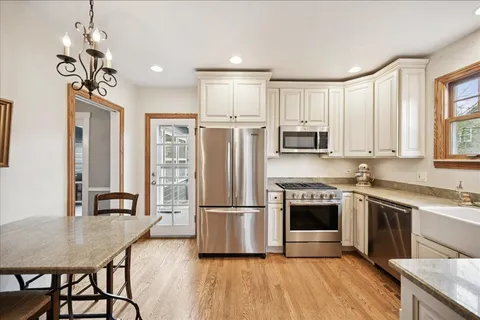 a kitchen with stainless steel appliances granite countertop a refrigerator a stove and a sink with wooden floor