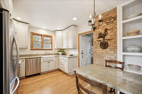 a kitchen with stainless steel appliances granite countertop a stove a sink dishwasher and a refrigerator with wooden floor