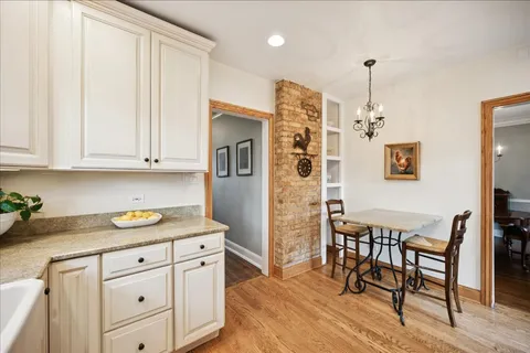a kitchen with stainless steel appliances granite countertop a sink a stove a dining table and chairs with wooden floor