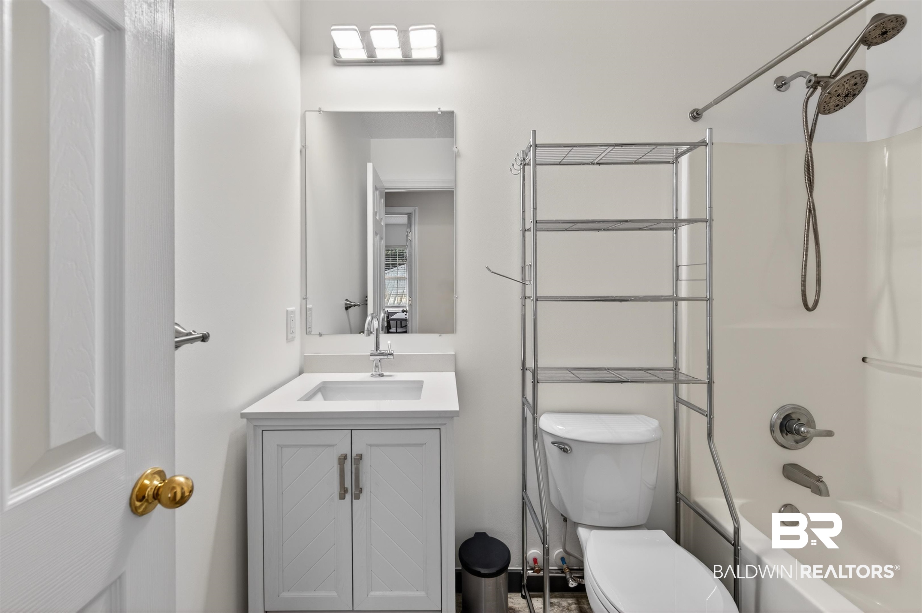 9624 North Bay Street Foley, AL 36535 - Photo 31 of 59 White vanity with a rectangular sink, undermount faucet, and a wall-mounted mirror