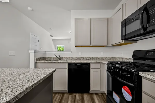 a kitchen with stainless steel appliances granite countertop a stove top oven a sink dishwasher and cabinets with wooden floor