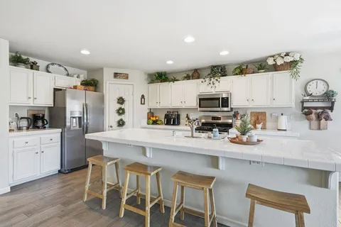 a kitchen with stainless steel appliances granite countertop a refrigerator a stove top oven a sink and cabinets