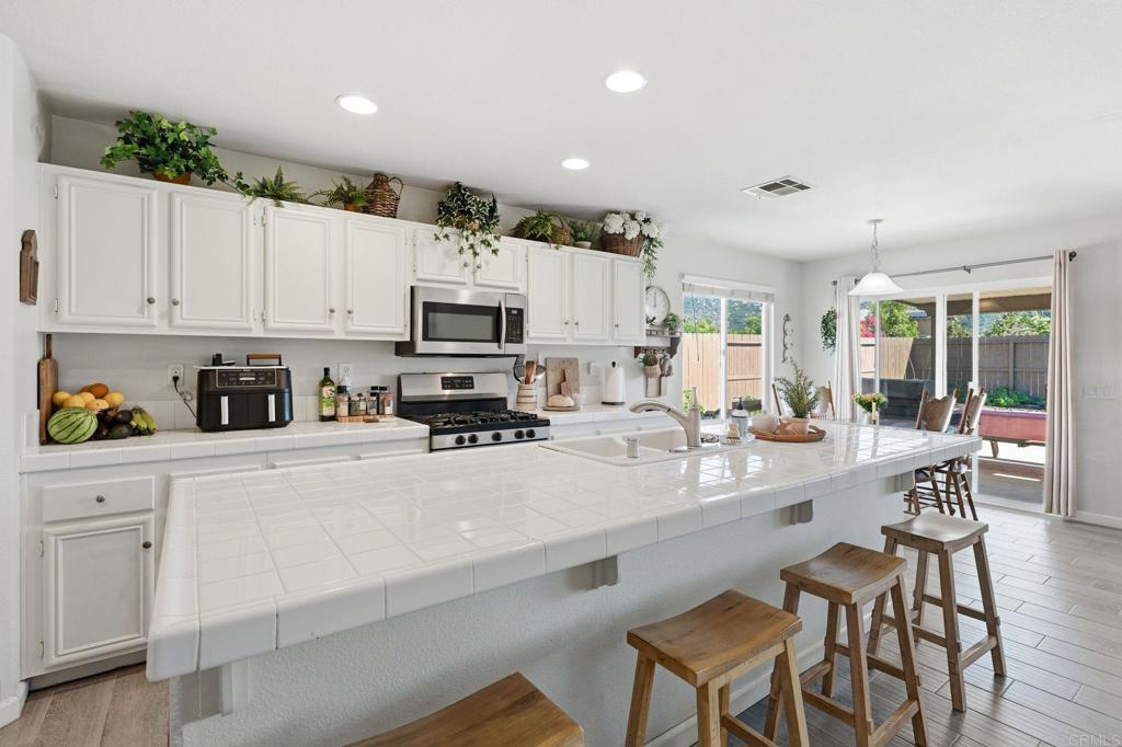 618 Jacks Creek Road Escondido, CA 92027 - Photo 9 of 48 a kitchen with stainless steel appliances a stove a sink a refrigerator white cabinets and chairs