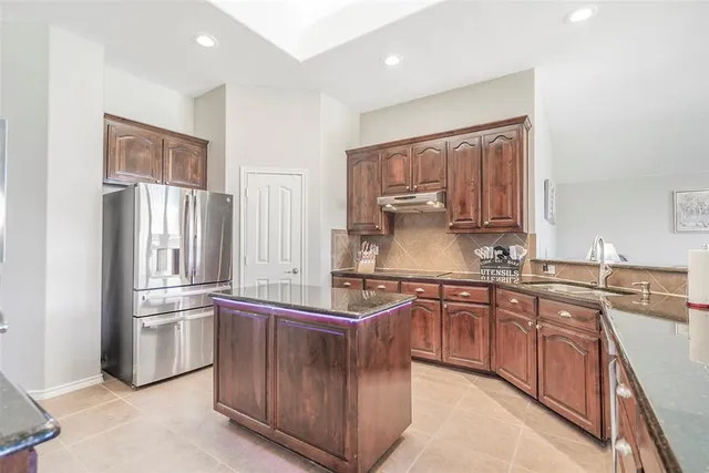 a kitchen with stainless steel appliances granite countertop a refrigerator and a stove top oven