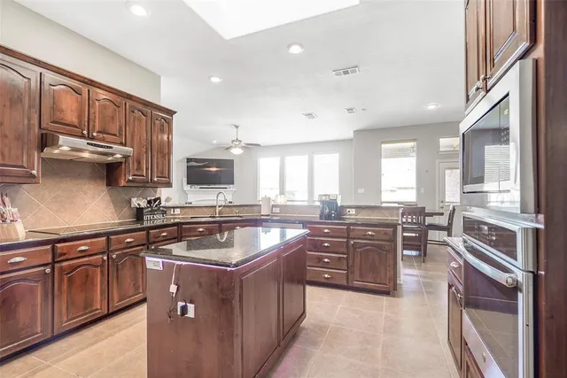 a kitchen with stainless steel appliances granite countertop a stove top oven a sink dishwasher a dining table and chairs