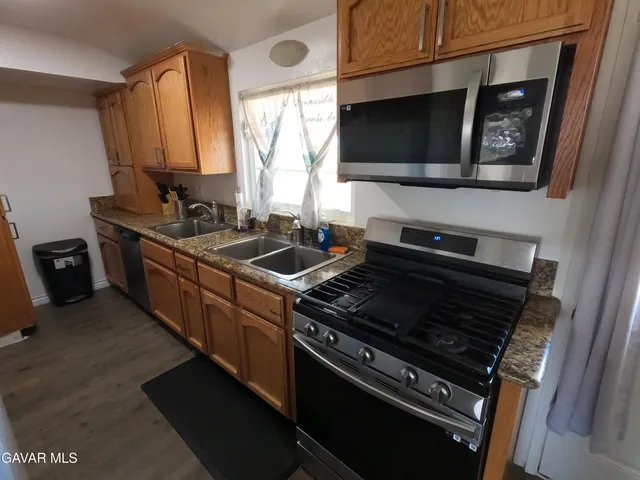 a kitchen with wooden cabinets stove top oven and sink
