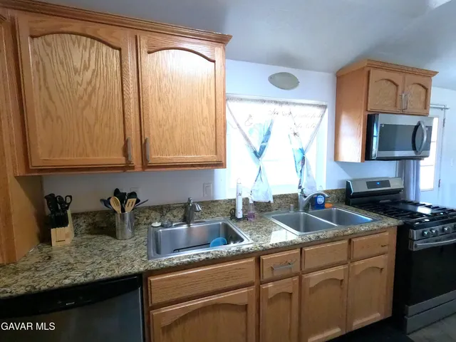 a kitchen with granite countertop a sink a stove and cabinets