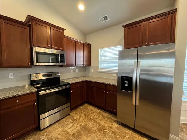 a kitchen with granite countertop a refrigerator stove and microwave