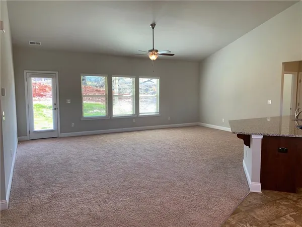 an empty room with windows and ceiling fan
