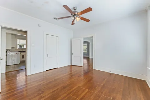 an empty room with wooden floor and a ceiling fan