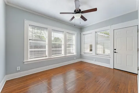 a view of an empty room with a window and wooden floor