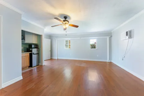 a view of an empty room with window and wooden floor